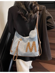 Large capacity denim tote bag in washed blue with brown leather M logo and shoulder straps