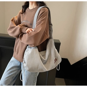 Detail of grey corduroy hobo bag showing drawstring texture and adjustable strap