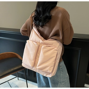 Detail of light pink crossbody tote bag with two front zipper pockets on model