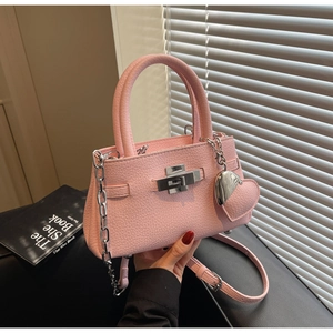Detail view of pink lychee leather handbag with silver lock and heart charm