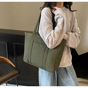 Quilted olive green tote bag in large capacity shown on shoulder with padded material