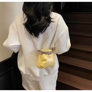 Detail of yellow kiss-lock mini bag with metal chain strap on a model background