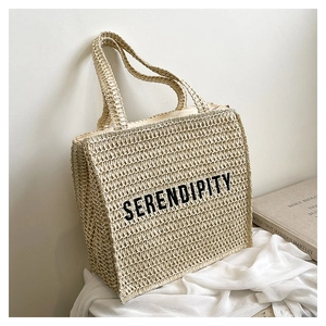 Close-up of woven straw tote bag with black Serendipity text on natural texture
