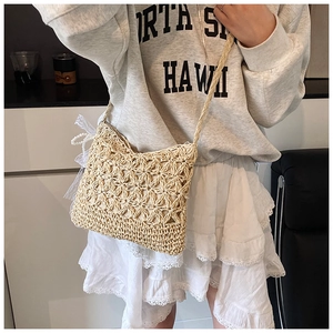 Detail der handgewebten beige Stroh-Umhängetasche mit Sternmuster und Spitzenschleife