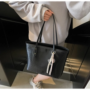Detail of black tote bag with wrinkled texture and tennis racket tassel charm