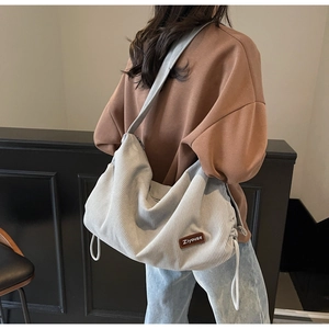 Detail of light grey corduroy shoulder bag with side drawstring and brand logo leather patch