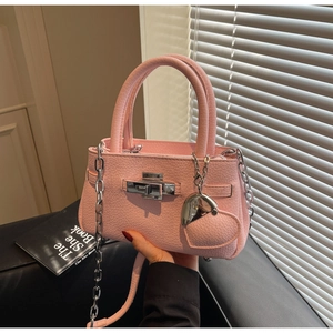 Detail of pink lychee leather bucket bag with silver twist lock and heart charm