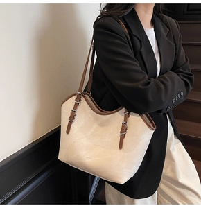 Close-up of the beige tote bag showing brown straps and adjustable silver buckles