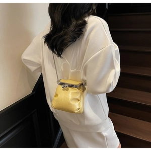 Detailed view of yellow mini crossbody bucket bag with glossy texture and chain strap