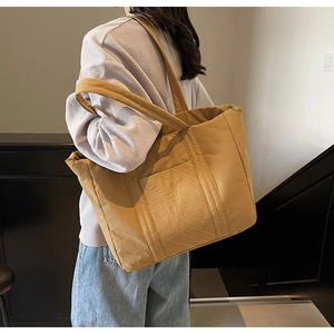 Detailed side view of a large khaki canvas tote bag showing the textured shoulder strap