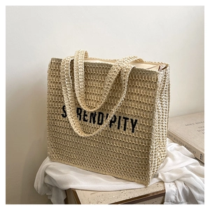 Close-up of beige woven beach tote bag with black Serendipity text and zip closure