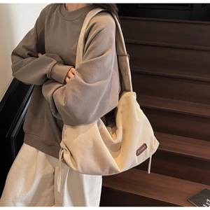 Detail of beige corduroy shoulder bag showing vertical texture and drawstring side decor