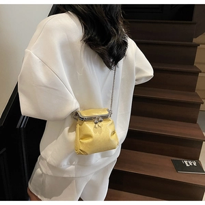 Detail of glossy yellow pleated crossbody bag with silver kiss-lock and metal chain