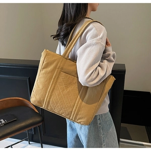 Detail of yellow quilted tote bag with diagonal stitching on shoulder for students
