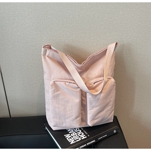 Detail of light pink padded nylon tote bag featuring double front zipper pockets