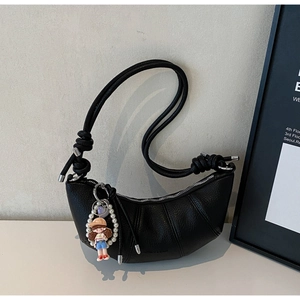 Detail of black crescent moon bag with textured pleated leather and pearl doll charm