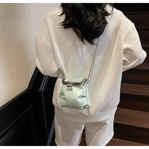 Rear view of mint green mini kiss-lock bag with metal chain on white sweatshirt