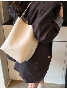 Minimalist cream white bucket bag in lychee leather worn with a dark blazer