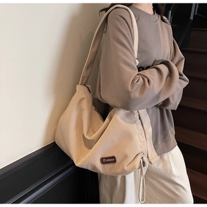 Detail of cream corduroy shoulder bag showing fabric texture and leather brand tag