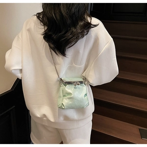 Detail of mint green crossbody bag with silver clasp and metallic chain strap
