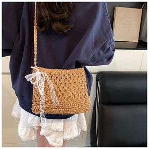 Detail der geflochtenen Strohtasche mit weißer Spitzenschleife und Perlen für den Sommer