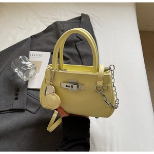 Detail of light yellow lychee grain leather bucket bag with silver chain and heart charm