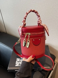 Elegant red cylinder bucket bag with woven texture, leather trim and silk scarf handle