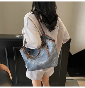 Detail of retro canvas tote bag showing grey-blue texture and brown leather handles