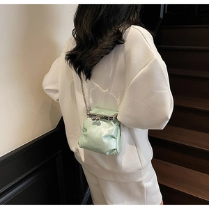 Close-up of mint green mini crossbody bag with vintage frame and metallic chain strap
