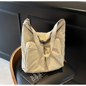 Detailed close-up of cream nylon tote bag with dual front zipper pockets and strap