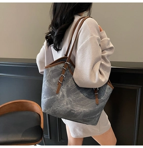 Detail of grey marble texture tote bag with brown adjustable straps and metal buckles