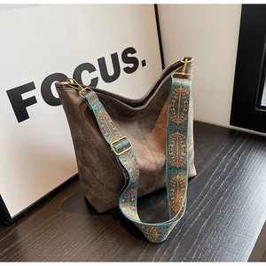 Close-up of deep brown suede tote bag featuring a vintage blue geometric wide strap