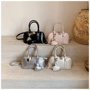 Four elegant Boston bags in black, pink, silver, and cream with heart-shaped pendants