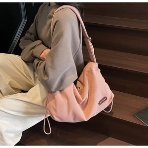 Pink corduroy crossbody bag featuring a large capacity design and side drawstring details