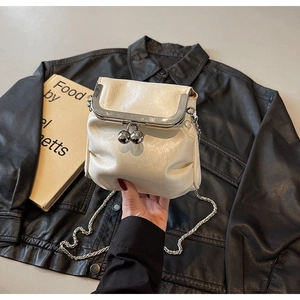 Detail of creamy white crossbody bag with silver clasp and pleated texture
