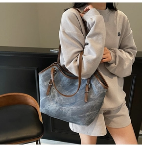 Detail of grey marble texture canvas tote bag with brown leather handles and brand logo