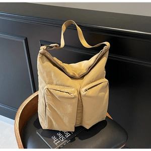 Detailed close-up of khaki nylon tote bag with dual front zipper pockets on a black chair