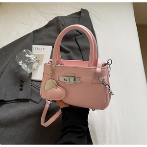 Detail of pink lychee leather bucket bag with silver twist lock and heart charm