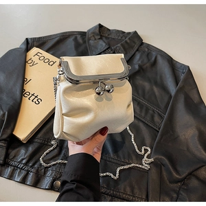 Close-up of cream vintage chain bag with silver metal kiss-lock closure and leather jacket
