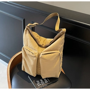 Detail of khaki nylon tote bag showing dual front zipper pockets on textured fabric