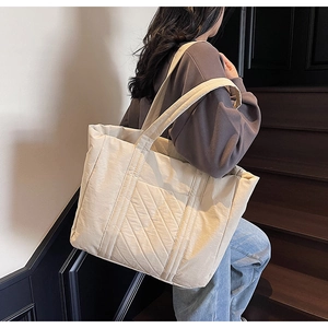 Detail of a large beige quilted tote bag showing fine stitching and spacious design