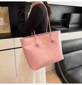 Close-up of pink leather tote bag featuring a small gold logo and slim shoulder strap