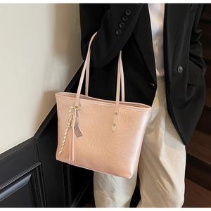 Detail of light pink pleated tote bag with silk scarf charm shown on shoulder