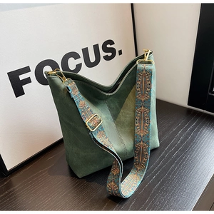 Detail of dark green tote bag featuring vintage stitching and colorful woven strap