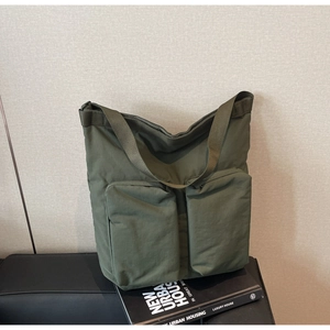 Detail of army green nylon tote bag featuring dual front pockets and wide shoulder strap