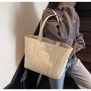 Close-up of cream quilted tote bag showing diagonal stitching and soft nylon texture