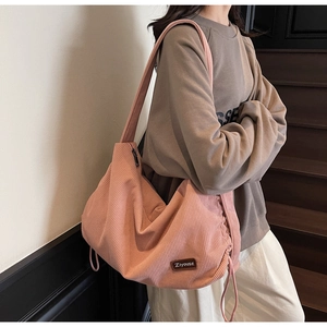 Detailed texture of pink corduroy tote bag with decorative side drawstring and leather logo