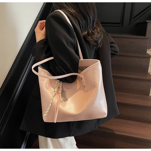Close-up of pink tote bag with metallic finish, decorative silk scarf and racket pendant
