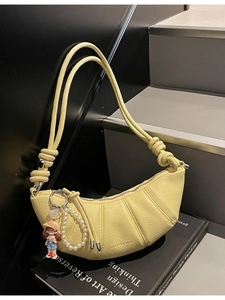 Pale yellow crescent bag with lychee texture featuring pearl chain and cute doll charm