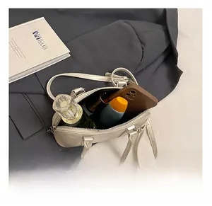 Minimalist beige shell bag interior showing storage for perfume and smartphone